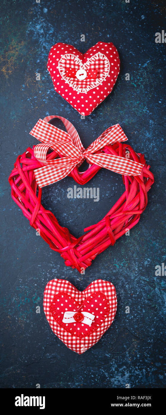 Il giorno di San Valentino con sfondo rosso squallido cuori fatti a mano su sfondo scuro. Banner verticale Foto Stock