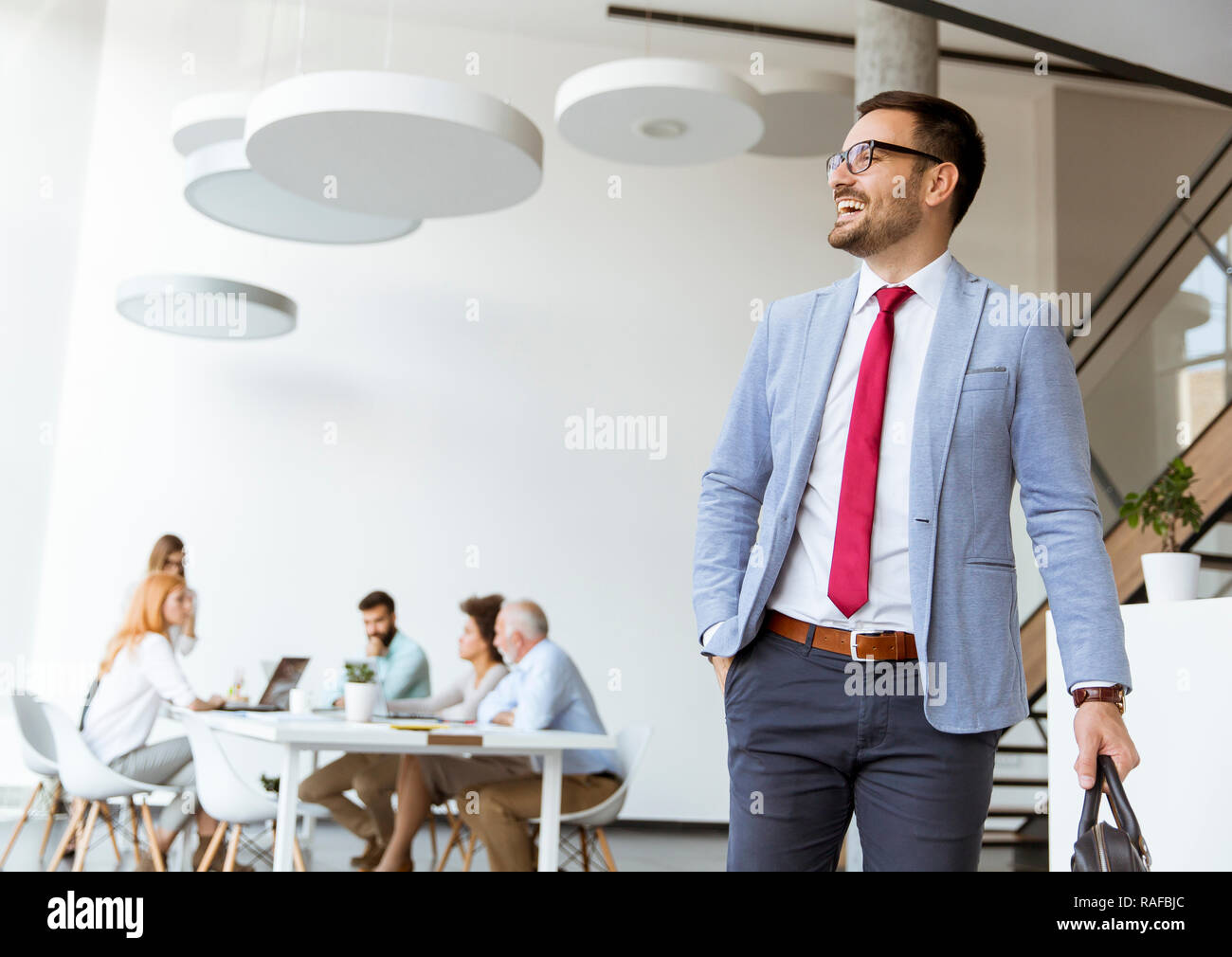 Imprenditore bello uscire da office mentre altri business persone aventi una riunione Foto Stock