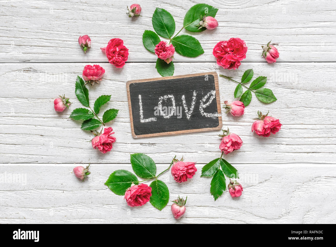 Composizione di fiori. telaio realizzato in rosa rosa fiori con amore iscrizione sulla lavagna. Il giorno di San Valentino sfondo. Piatto, laici vista superiore Foto Stock