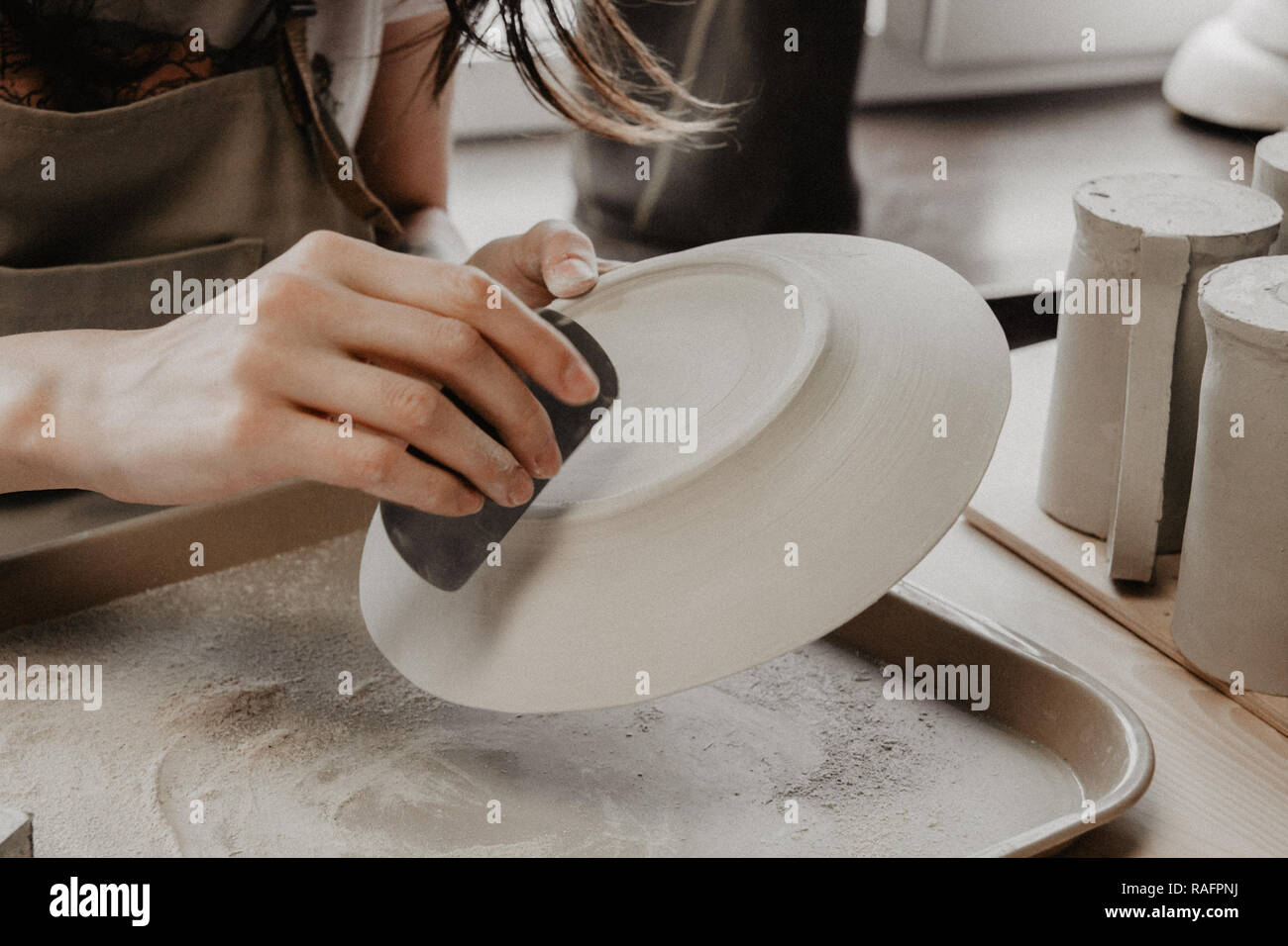Donna fare ceramica. Vista dettagliata del processo di levigatura a piastra di argilla Foto Stock