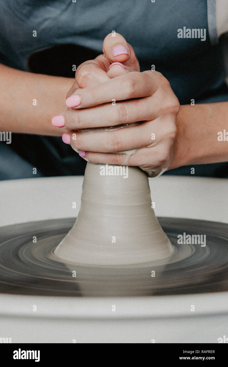 Creazione di un vaso o in un vaso di argilla bianca di close-up. Donna mani rendendo brocca di argilla su potter ruota. Foto Stock
