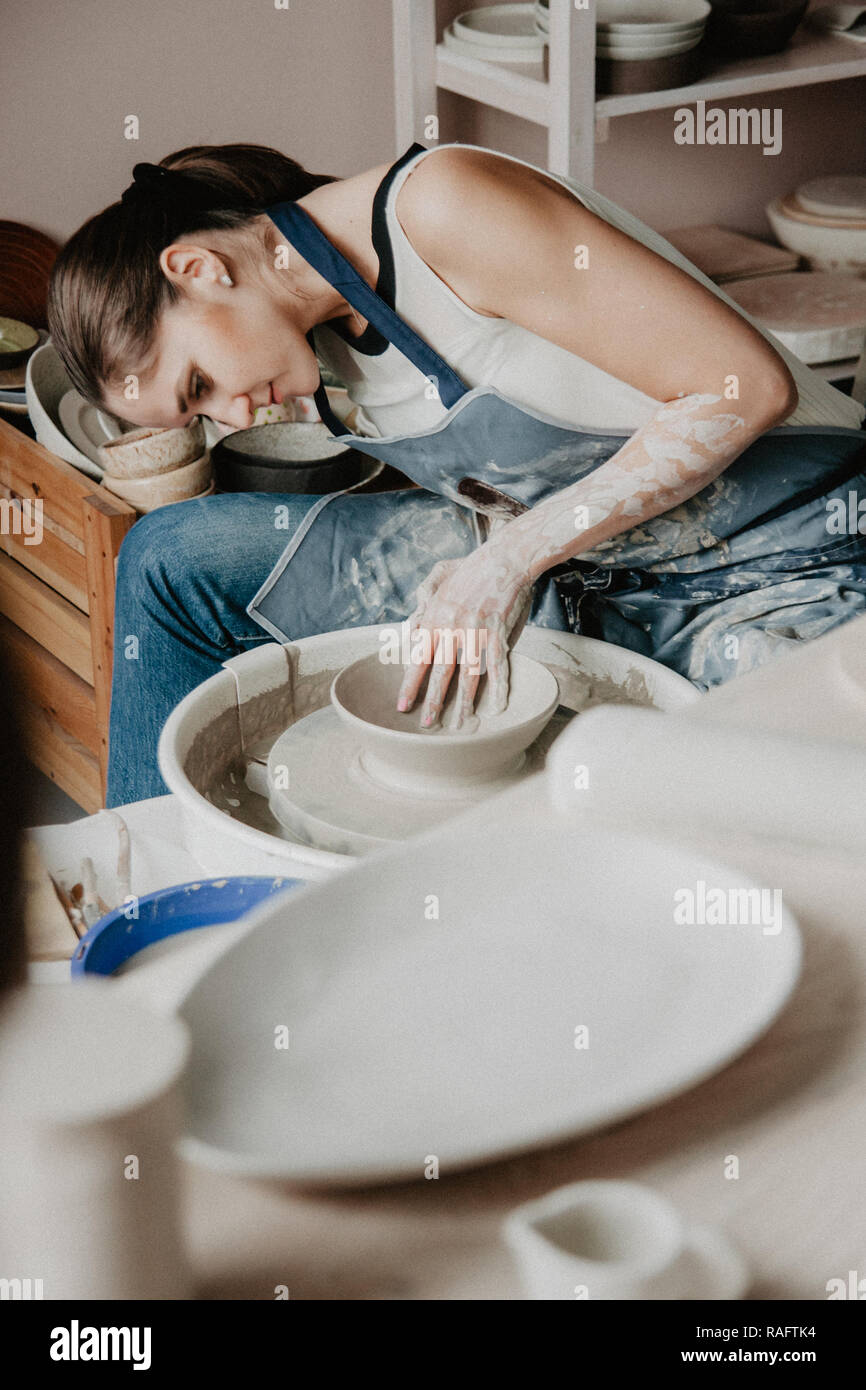 Creazione di un vaso o in un vaso di argilla bianca di close-up. Donna mani rendendo brocca di argilla su potter ruota. Foto Stock