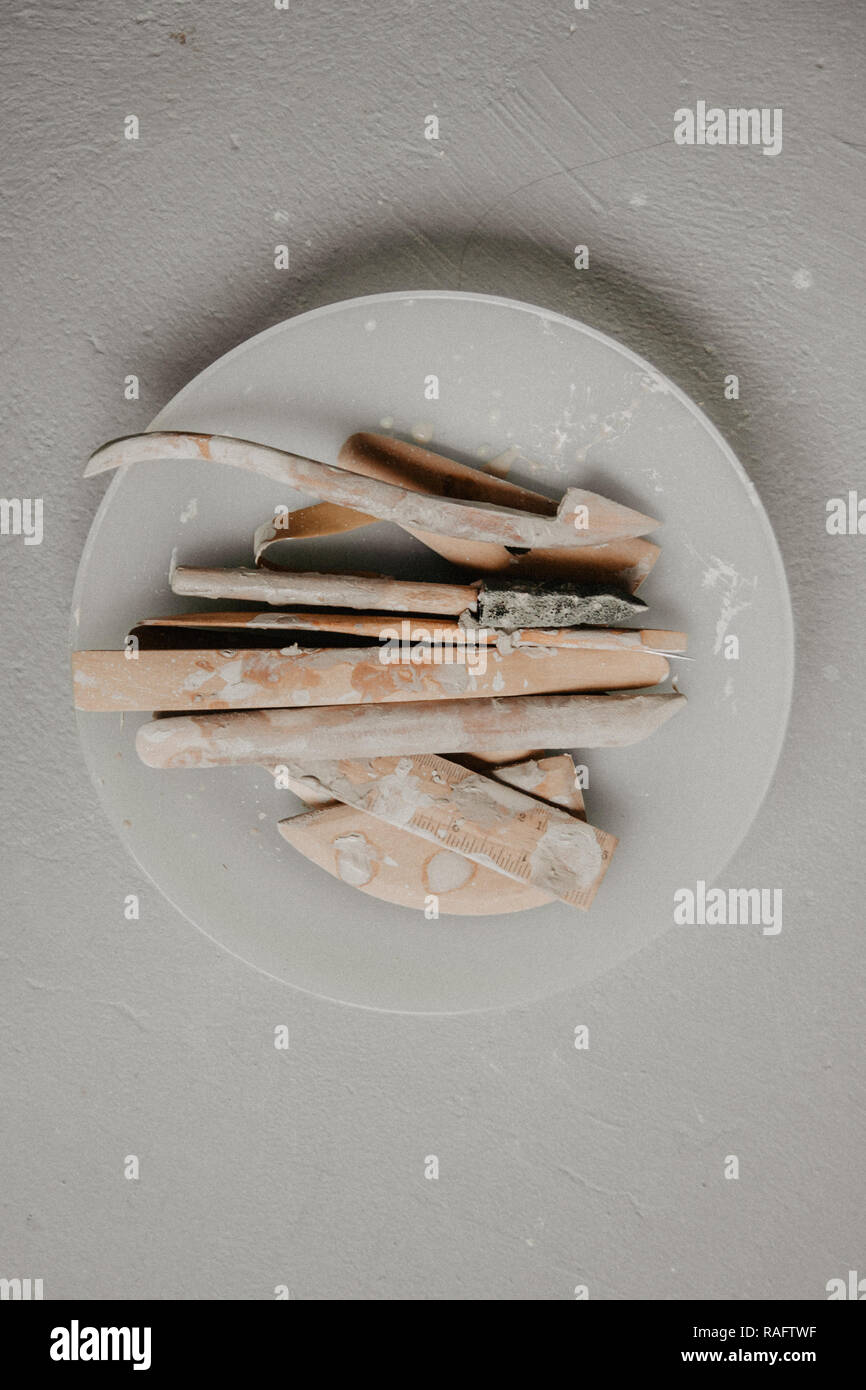 Set di sporco arte e artigianato scultura strumenti sul tavolo di legno nel laboratorio di ceramica su sfondo chiaro Foto Stock