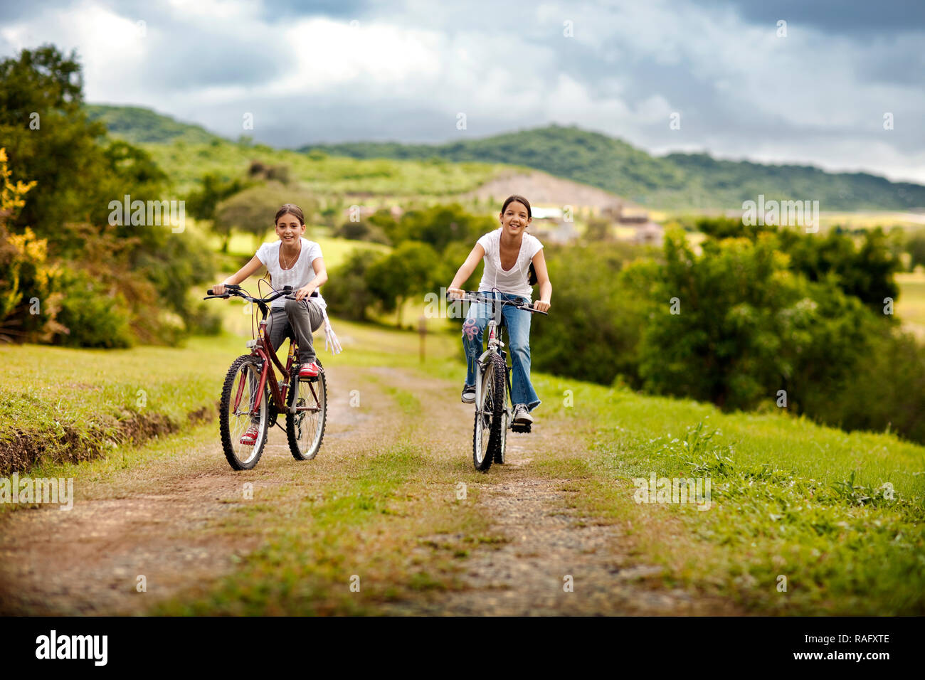 Due ragazze godendo la bicicletta sulla strada di ghiaia. Foto Stock