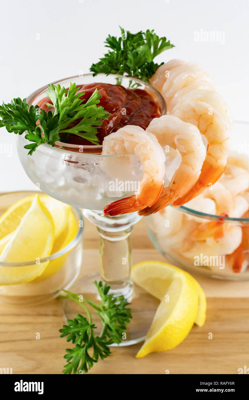 Cocktail di gamberetti: vista laterale superiore del bicchiere Margarita con gamberetti agganciata sulla parte esterna del vetro con salsa cocktail e guarnire all'interno. I limoni e prezzemolo Foto Stock