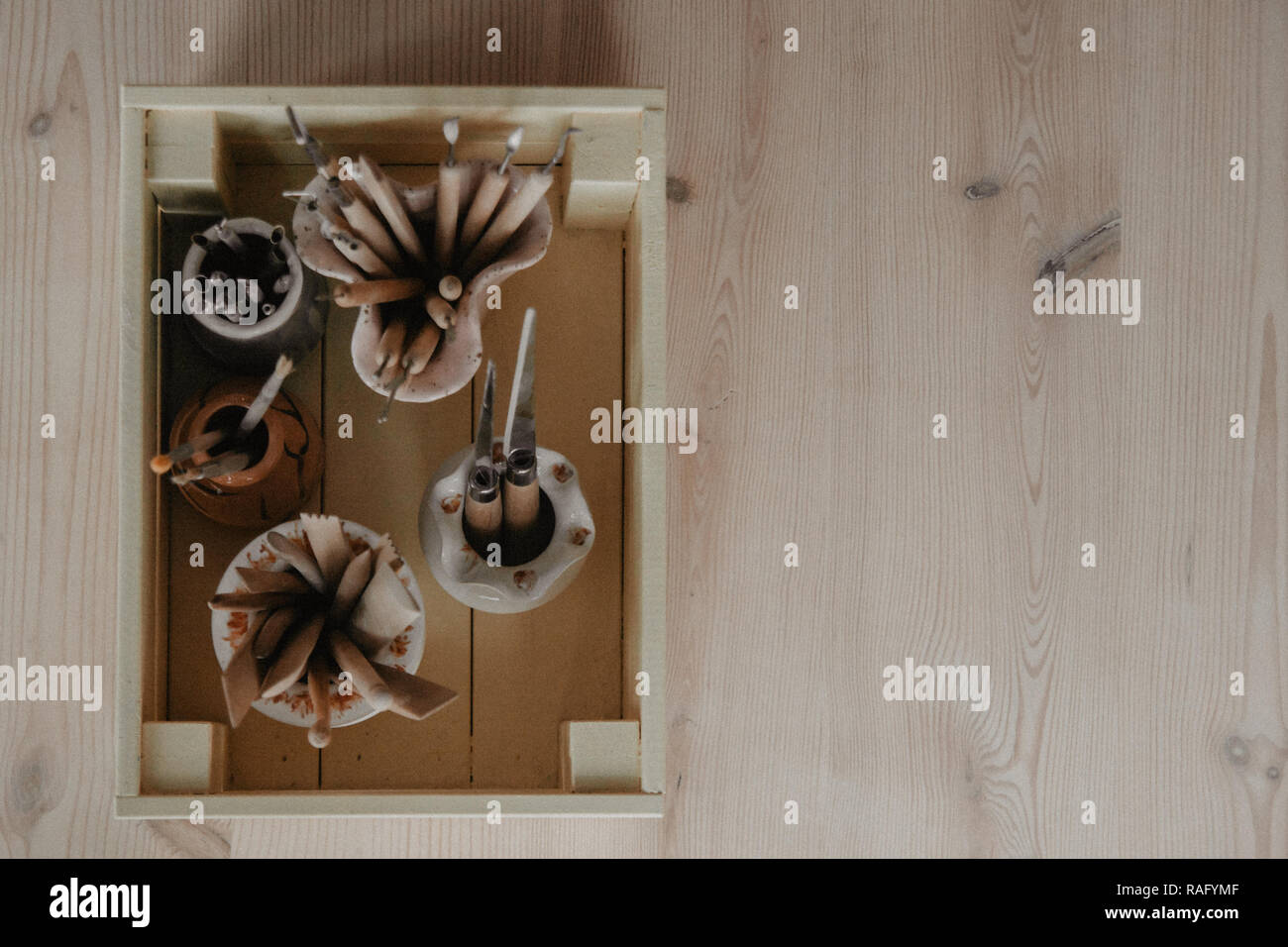 Set di sporco arte e artigianato scultura strumenti sul tavolo di legno nel laboratorio di ceramica su sfondo chiaro Foto Stock