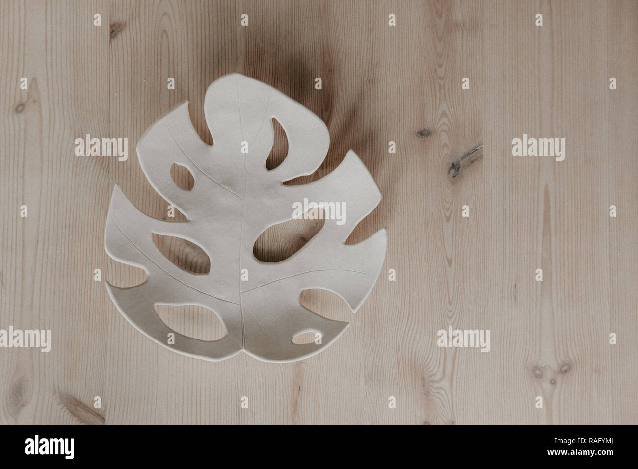 Piastra di argilla in forma di Monstera, su uno sfondo di legno con copia spazio per foto maipulations Foto Stock