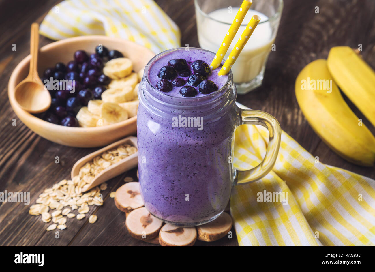 Frullato di mirtilli con banana e fiocchi di avena in vaso su legno rustico sfondo. Foto Stock