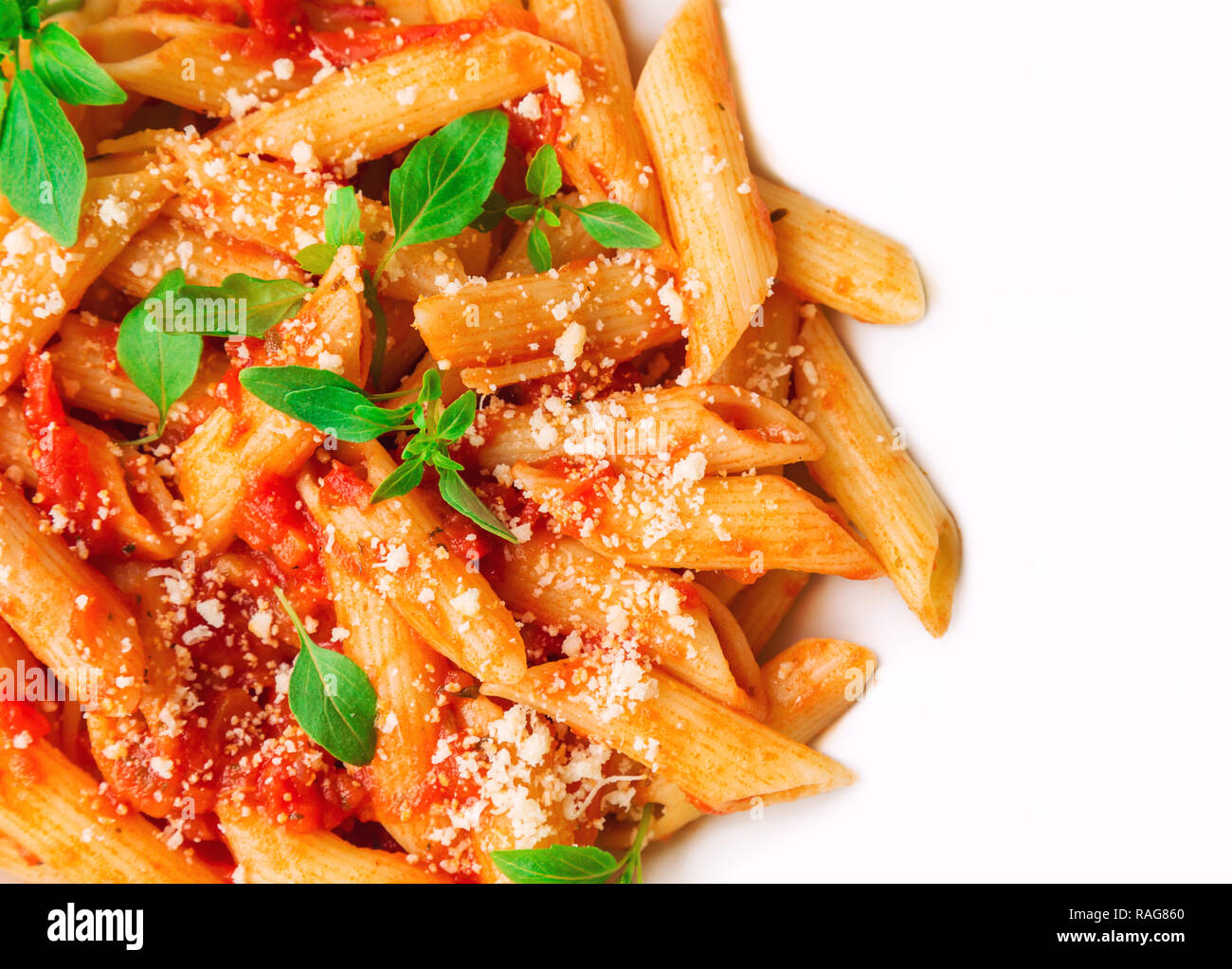 Penne pasta in salsa di pomodoro con basilico e parmigiano isolato su bianco. Vista dall'alto. Foto Stock