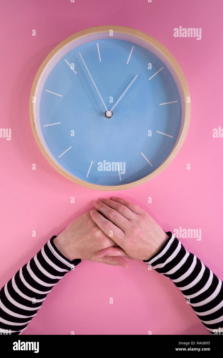 Mani femminili e il grande orologio su sfondo rosa, materno invecchiamento e menopausa, la cura della salute e di prevenzione delle malattie concetto Foto Stock