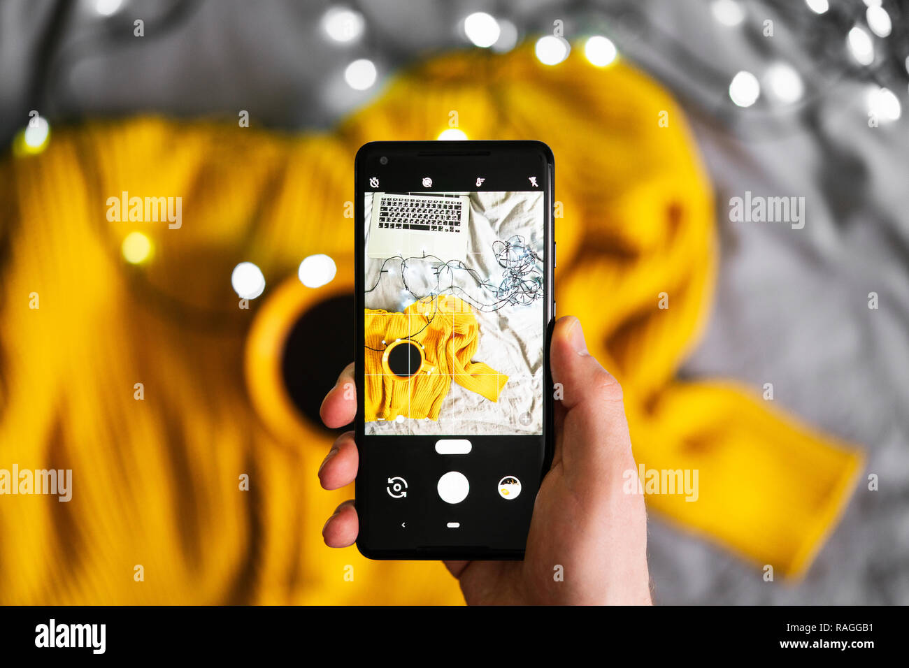 Chiusura del telefono mobile rendendo le foto del maglione e tazza di tè. Foto Stock