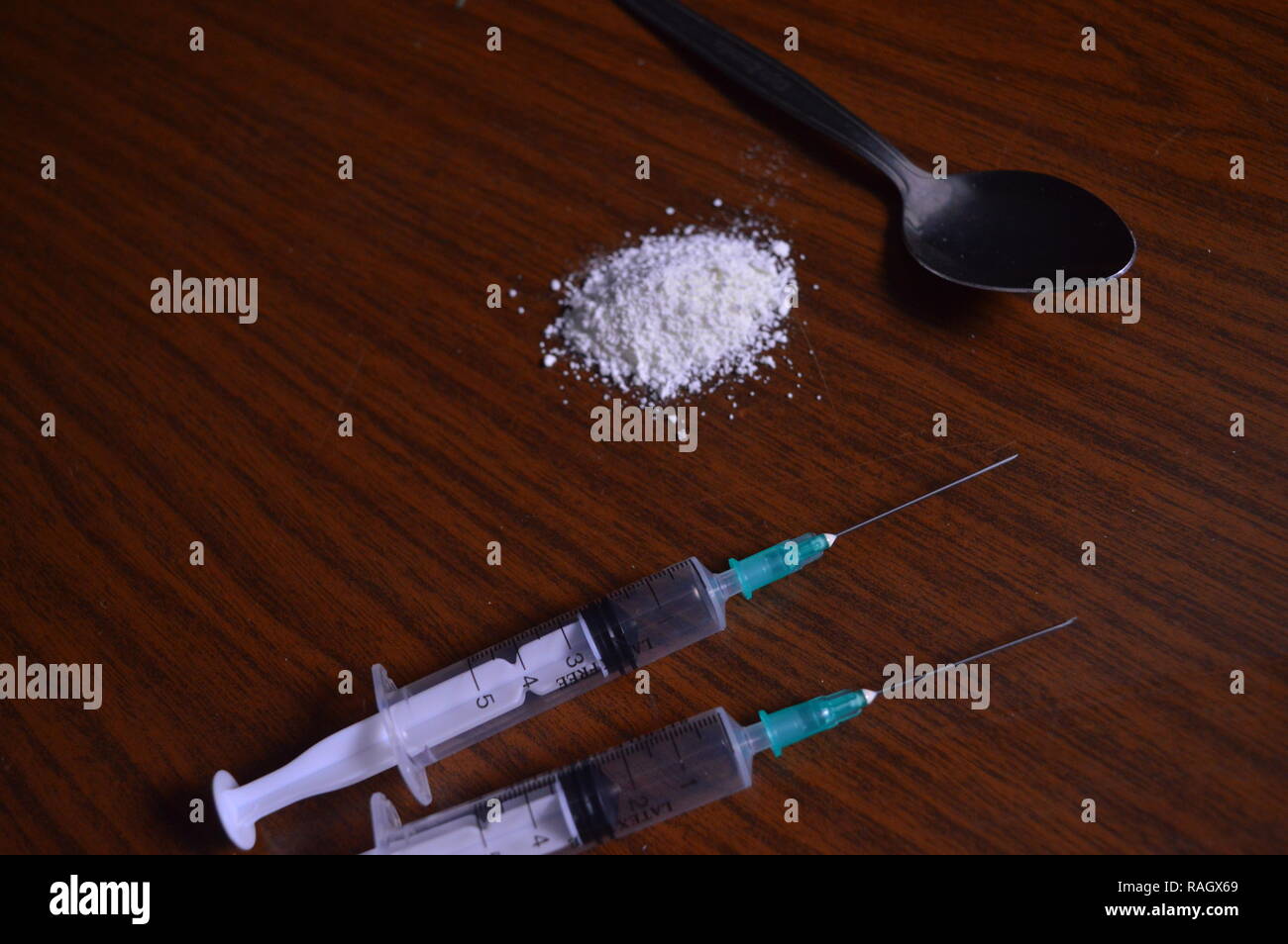 Narcotici essendo preparato. Aghi, cucchiaio e polvere bianca su una tabella. Foto Stock