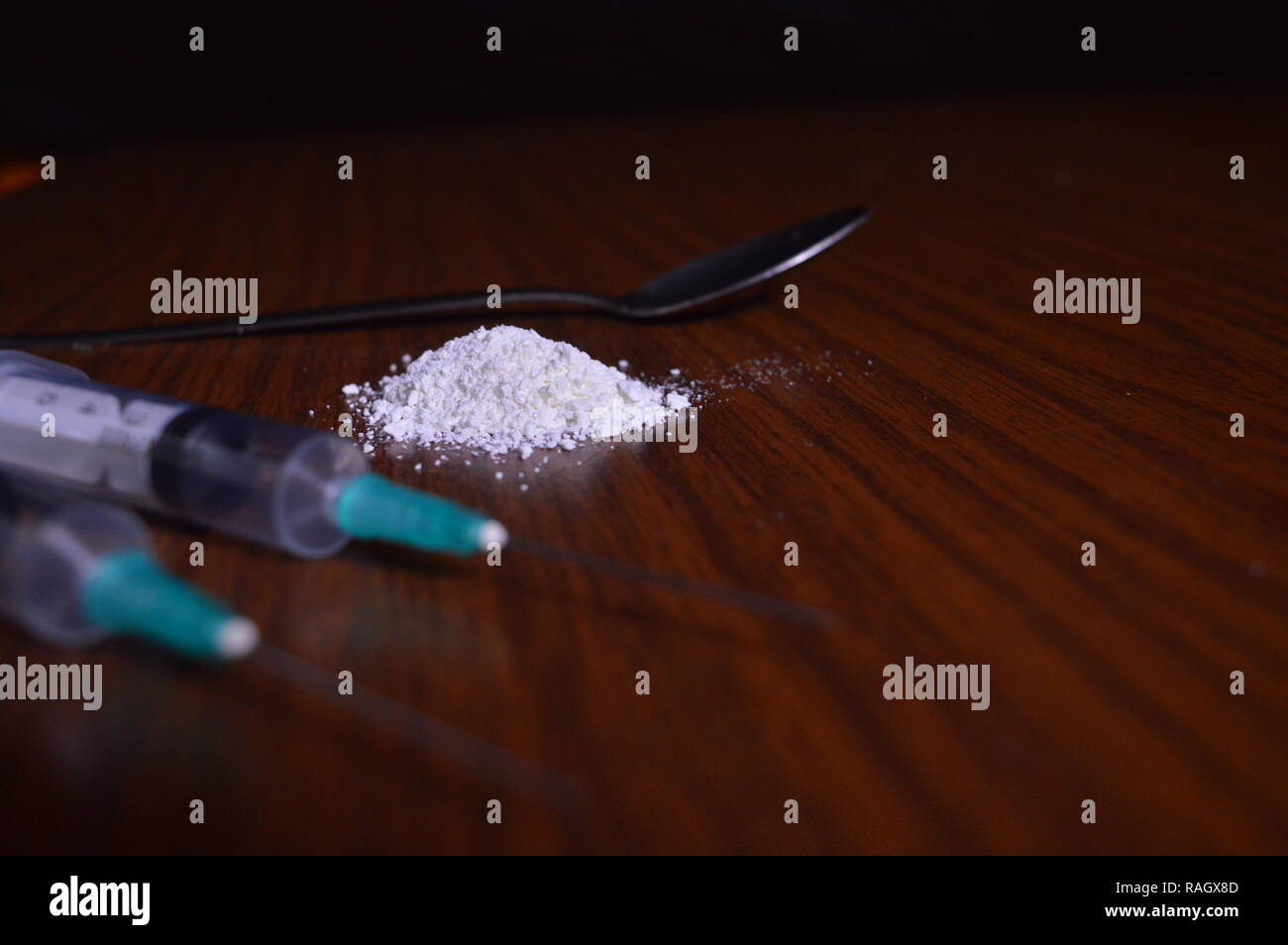 Narcotici essendo preparato. Aghi, cucchiaio e polvere bianca su una tabella. Foto Stock