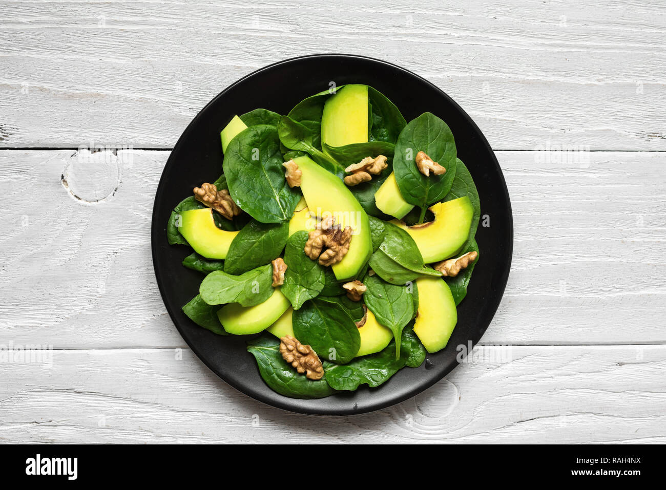 Vegano con insalata di avocado, spinaci e noci in piastra nera. cibo sano. vista superiore Foto Stock