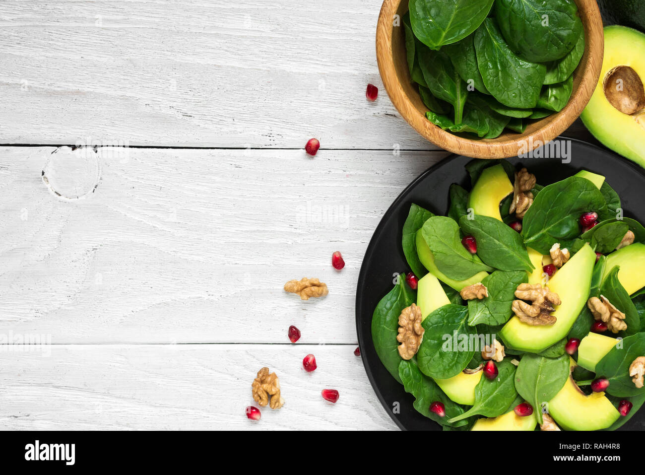 Vegetariano fresca insalata di avocado, spinaci, melograno e noci in piastra nera. cibo sano. vista superiore con spazio di copia Foto Stock