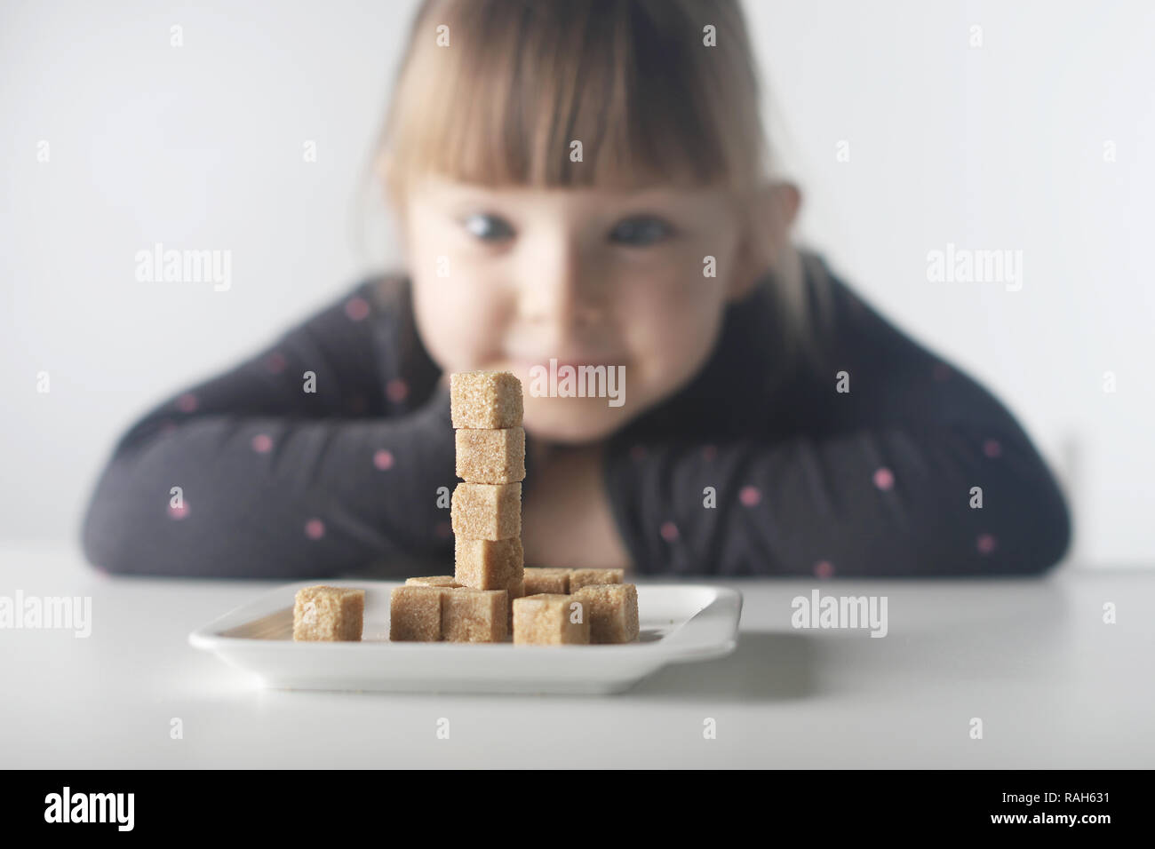 Bambino, cubetti di zucchero. Il problema del consumo eccessivo di zucchero da parte di bambini di età inferiore ai dieci anni. Foto Stock