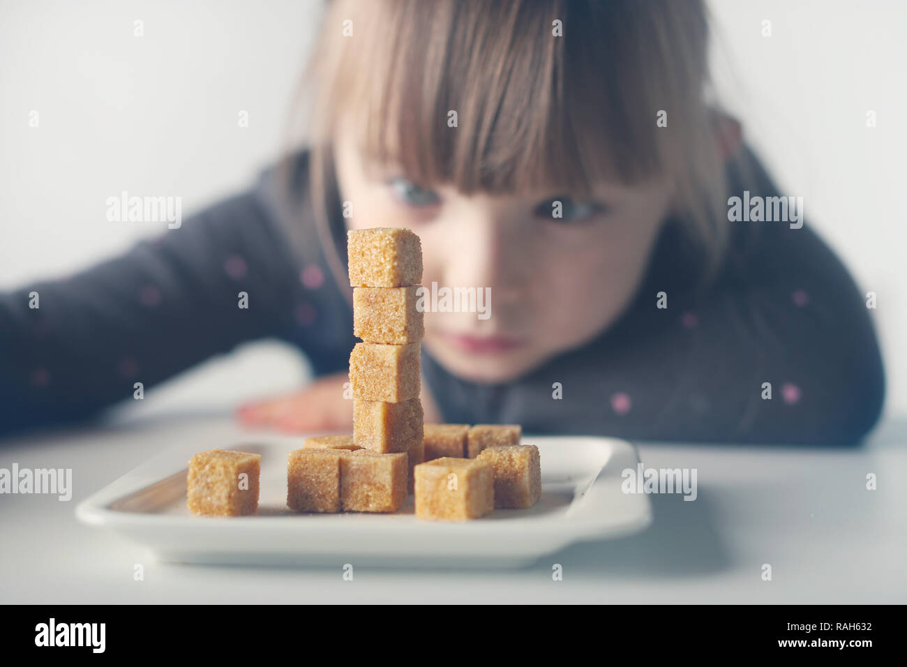 Bambino, cubetti di zucchero. Il problema del consumo eccessivo di zucchero da parte di bambini di età inferiore ai dieci anni. Foto Stock