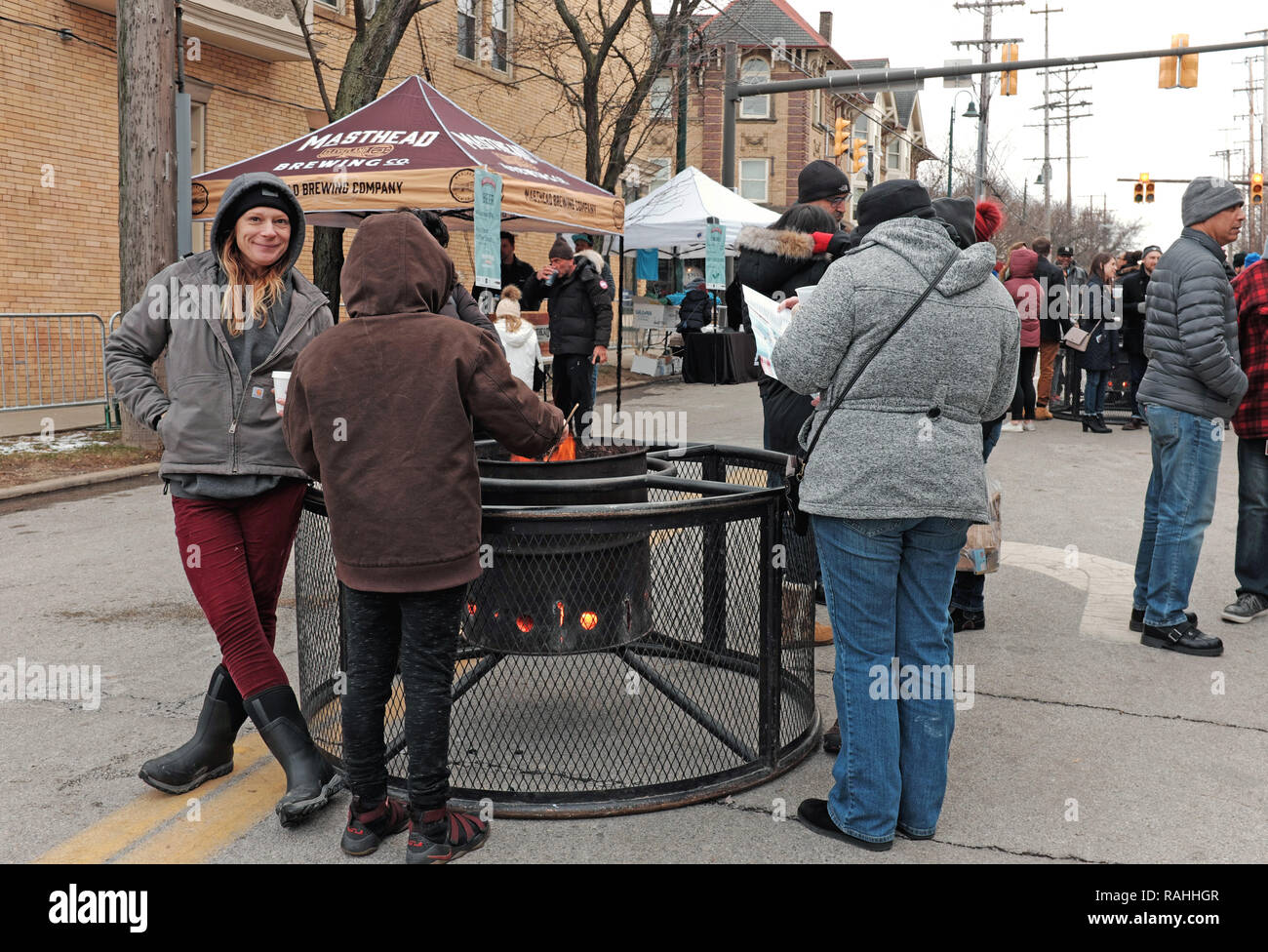 I visitatori della terza edizione Gordon Square Wintertide Holiday Festival di rimanere caldo intorno al fuoco all'aperto pit in Cleveland, Ohio, USA. Foto Stock