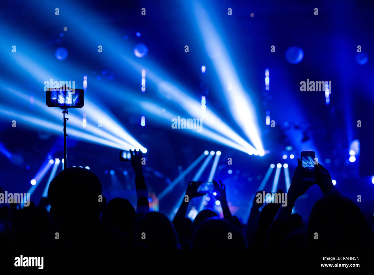 Sagome di folle di spettatori in un concerto con gli smartphone nelle loro mani. La scena è splendidamente illuminato da faretti. Foto Stock