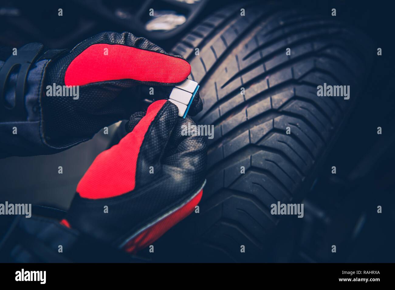 Industria automobilistica. Macchina di equilibratura di una ruota e pneumatico Peso in mano dei lavoratori. Foto Stock