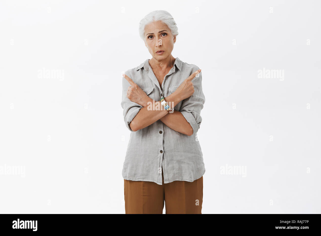 Vecchia donna non può decidere in quale modo migliore. Ritratto di confuso certi nonnina con i capelli grigi in camicia casual bracci di incrocio sul petto rivolto a sinistra e a destra avendo difficoltà nel rendere la decisione o la scelta Foto Stock