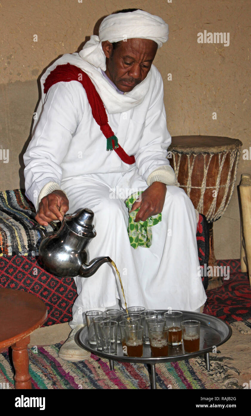 Gnawa uomo tribale in Khamlia, Merzouga che serve tè in Marocco tradizionale cerimonia del tè Foto Stock