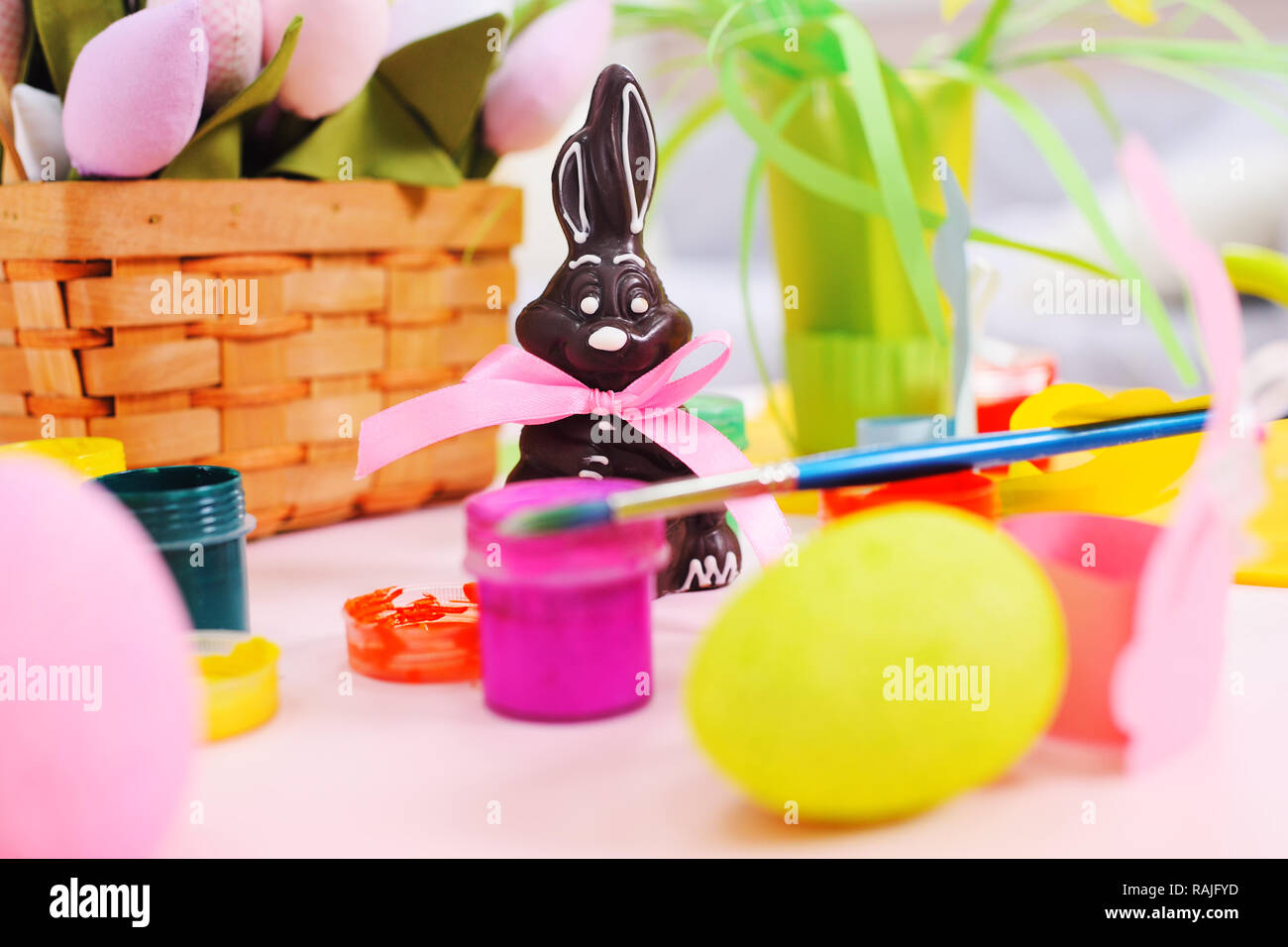 Il cioccolato coniglietto di pasqua sullo sfondo della Pasqua decor, fiori, dipinto di uova, barattoli di vernice. Foto Stock