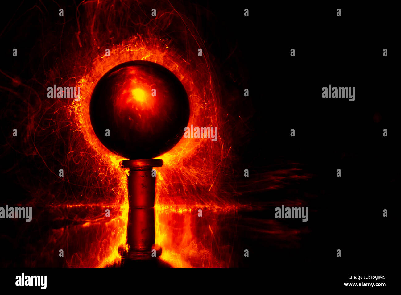 Luci rosse in forma di minuscole fibre illuminanti dietro una sfera trasparente. La pittura di luce la fotografia. Foto Stock