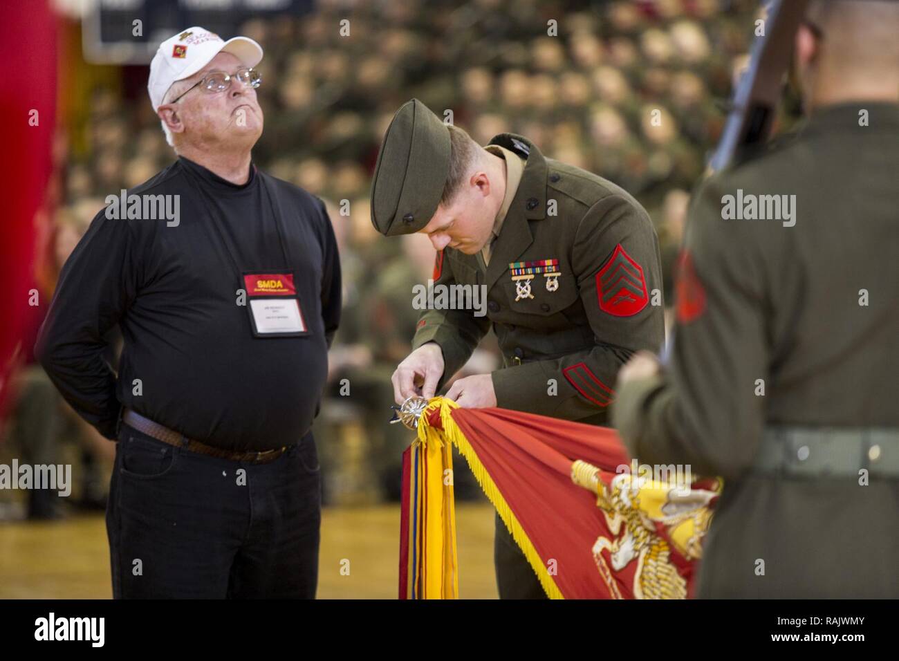 Un U.S. Marine con seconda divisione Marine (2d MARDIV), a destra lungo con 2d MARDIV veterano, attribuisce una battaglia streamer per l'unità guidon durante il 2D MARDIV 76th battaglia colori riconsacrazione e cerimonia di premiazione presso il Memorial Goettge Field House, Camp Lejeune, N.C., Feb 10, 2017. Stati Uniti Marines, i marinai e i civili hanno partecipato alla cerimonia di riflettere sui successi della divisione negli ultimi 76 anni. Foto Stock