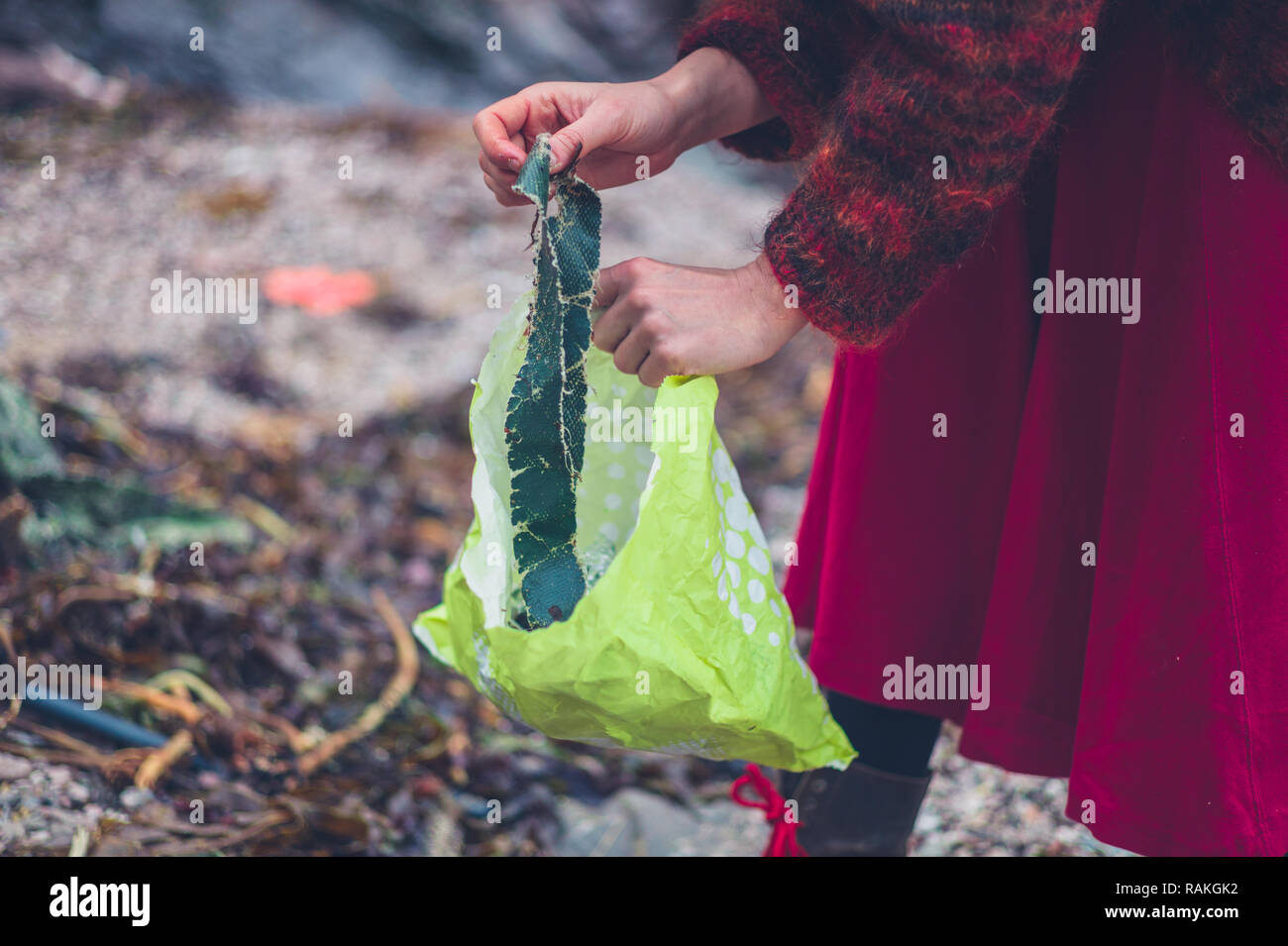 Una giovane donna è la pulizia di rifiuti di plastica sulla spiaggia Foto Stock