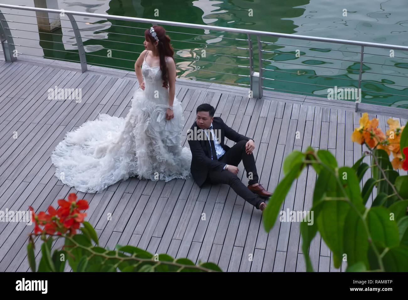 Una coppia di novelli sposi in Singapore rilassante durante un matrimonio photo shoot, in caso Plaza, Marina Bay, un posto popolare per la fotografia di matrimonio Foto Stock