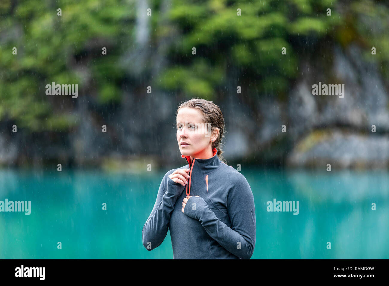 Ragazza in piedi sotto la pioggia su acque cristalline Foto Stock