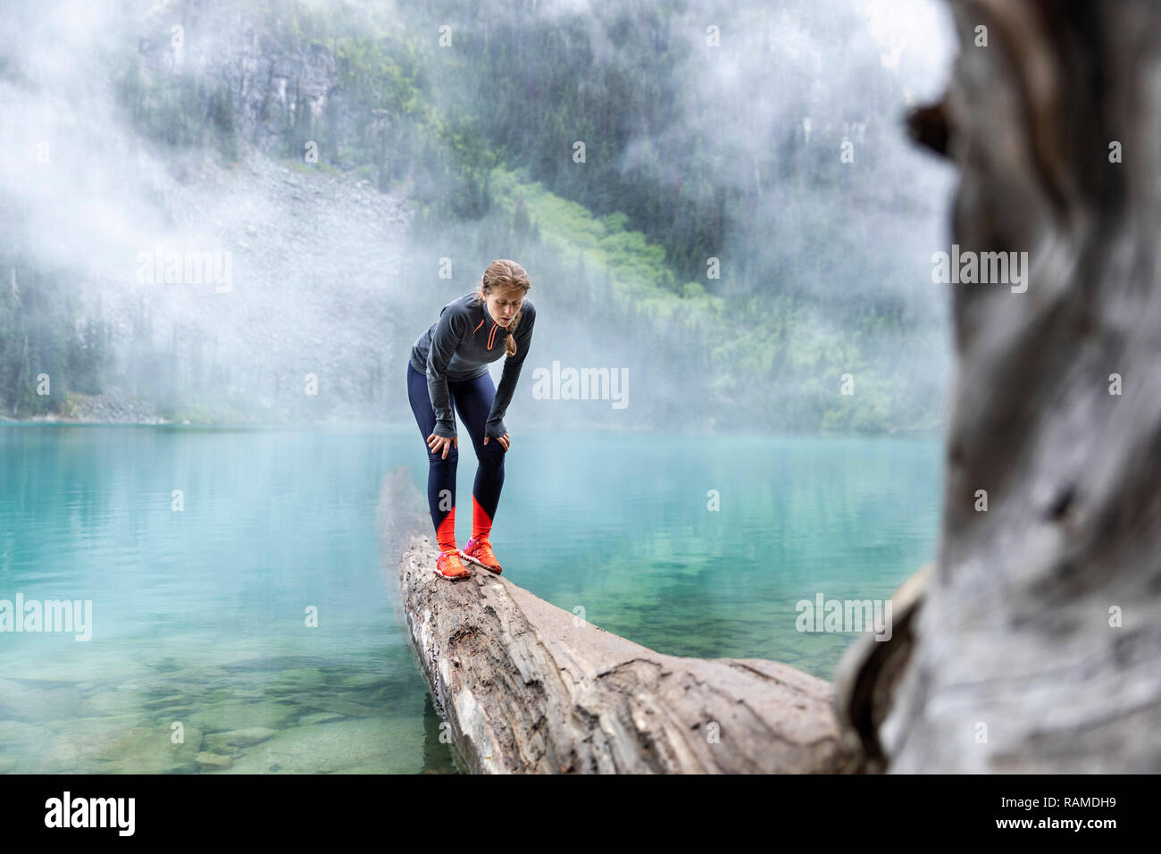 Donna in piedi su un tronco di albero sui laghi di Joffre Foto Stock