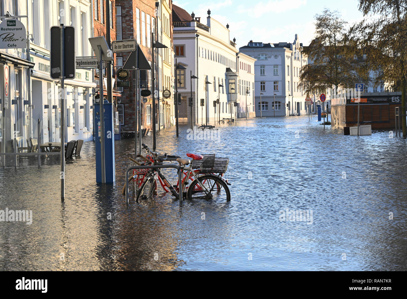 Lubecca, Germania, 2 gennaio 2019: biciclette in piena del fiume Trave con acqua alta nel centro storico di Lubecca, Germania, cielo blu, c Foto Stock