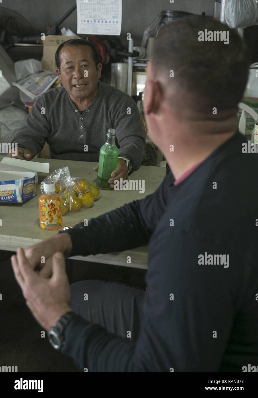 Kinjo Bokusei prende una pausa dal lavoro sulla sua azienda vicino a Camp Hansen, Okinawa, in Giappone, febbraio 23, 2017, per parlare con Gunnery Sgt. Todd Groves. Boschetti, da Fulton, Missouri, era un allevatore di suini crescono e ora i volontari a prendersi cura della terra e gli animali su Kinjo's farm. Groves è un capo di manutenzione con piccole imbarcazioni plotone di riparazione, operazioni Expeditionary Gruppo di addestramento, III Marine Expeditionary Force. Foto Stock