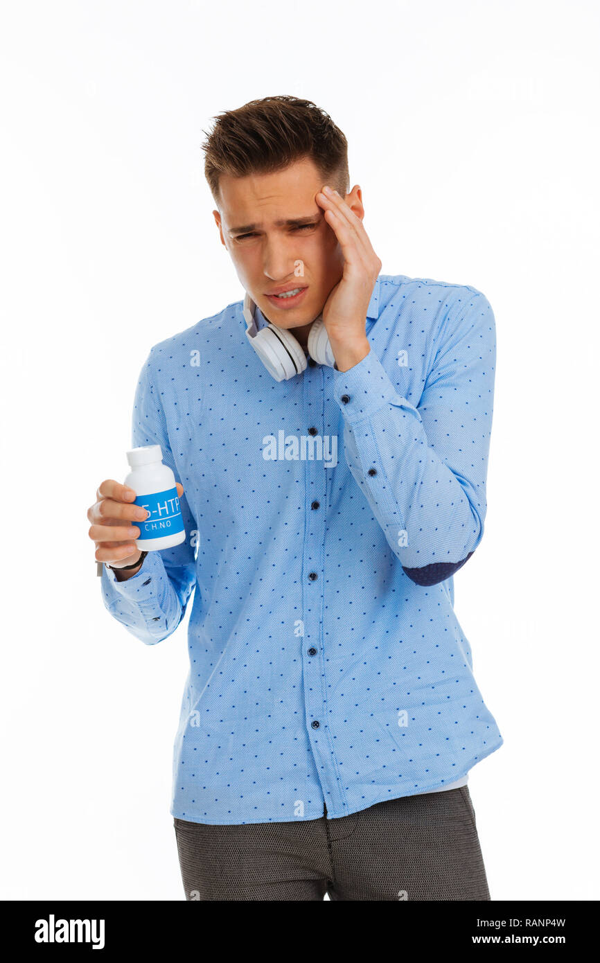 Cupa bella giovane uomo toccando il suo fronte Foto Stock