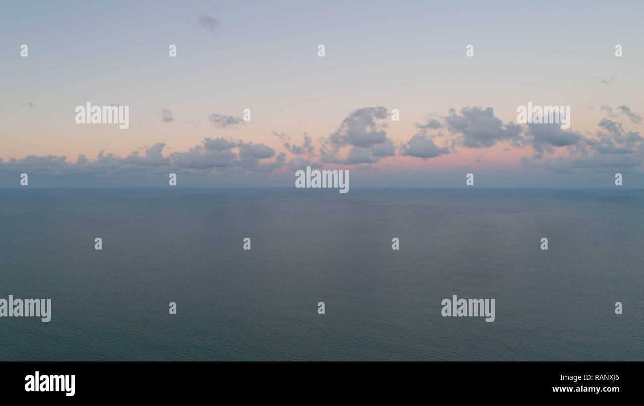 Drone foto immagine aerea tranquilla mattina presto vista giorno nuvoloso oceano orizzonte allo spuntar del giorno con bellissimi colori di Alba Sun cercando di rompere le nuvole. Foto Stock