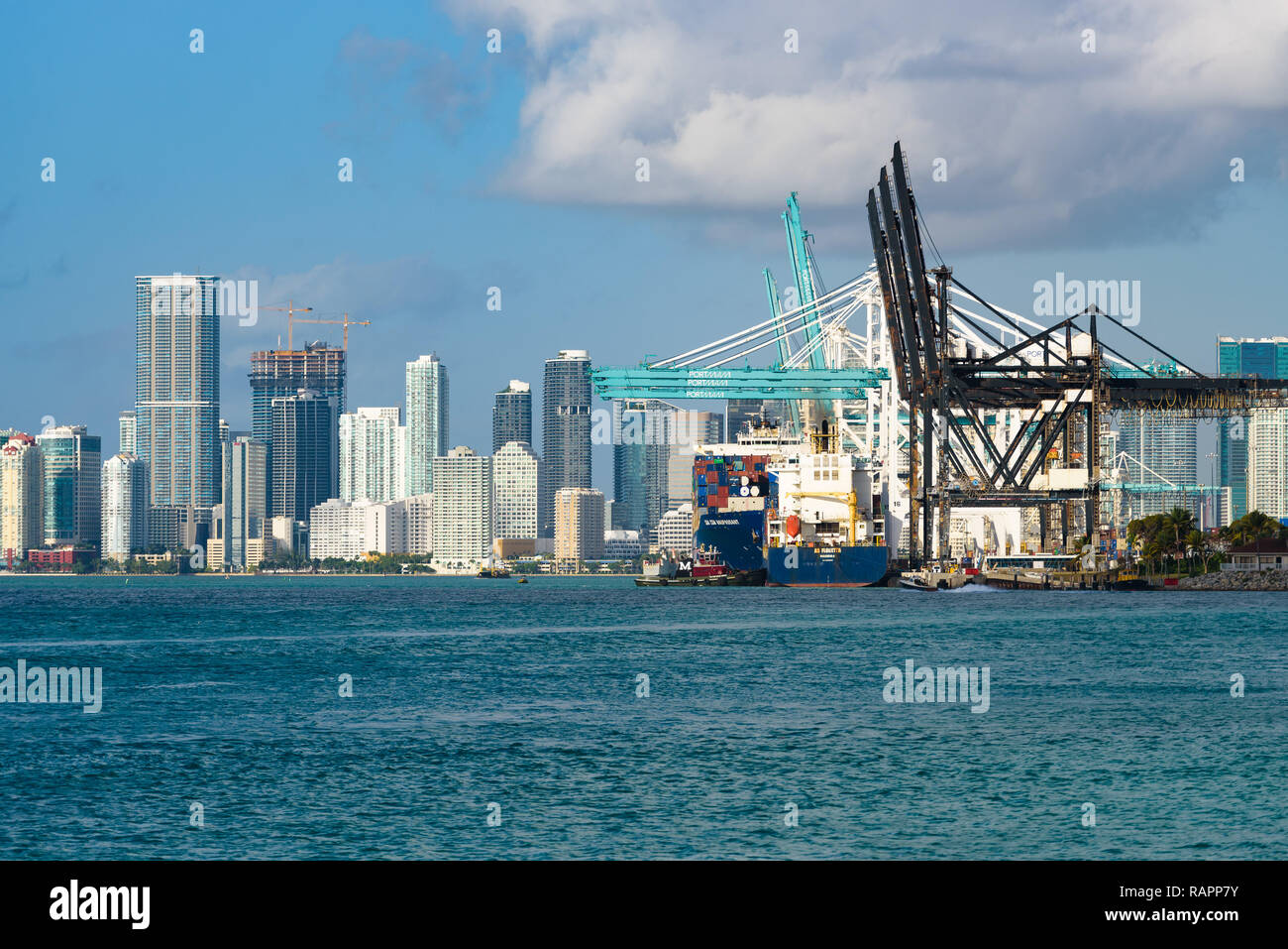 Miami Beach, Florida - Vista del Porto di Miami con grandi navi container e gru. Sullo sfondo i grattacieli di lo skyline del centro cittadino. Foto Stock