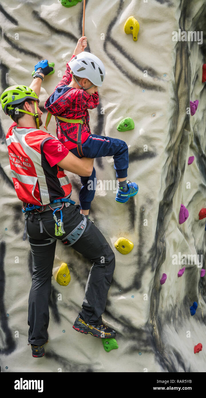 Istruttore maschio lavora con un giovane ragazzo sulla parete di arrampicata Foto Stock