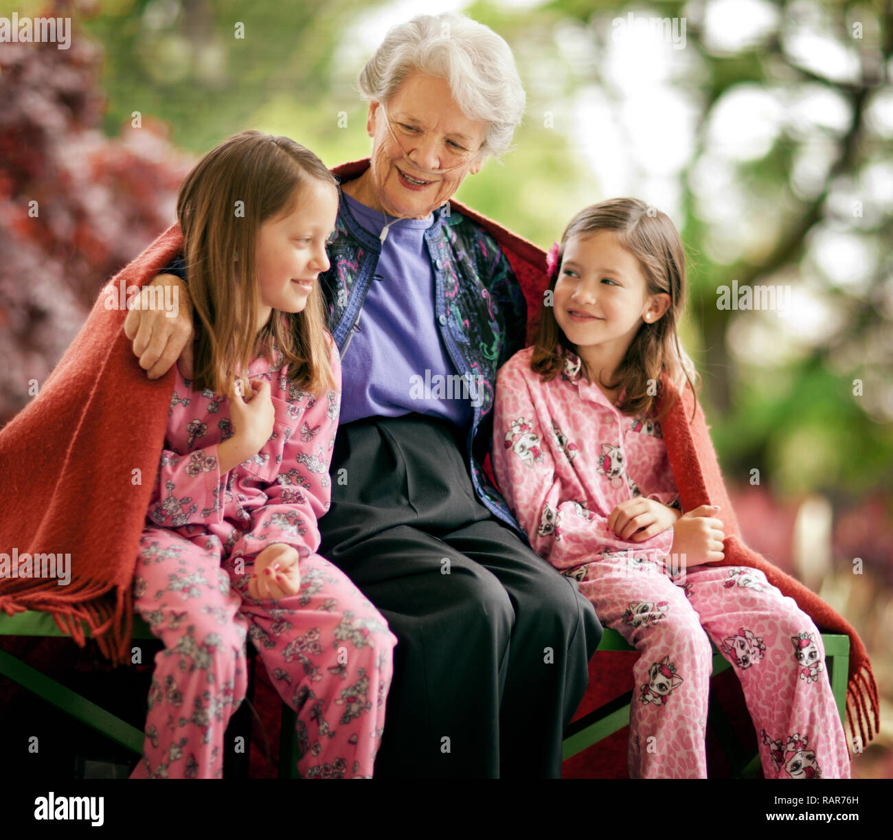 Senior sorridente donna seduta con i suoi due nipoti. Foto Stock