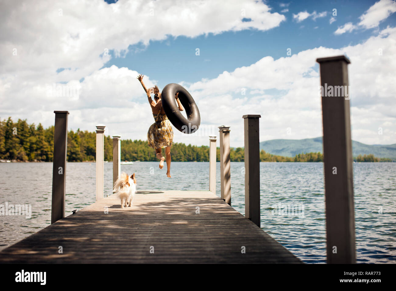 Vista posteriore della giovane donna che sta per saltare fuori un pontile completamente vestito, con un tubo interno. Foto Stock