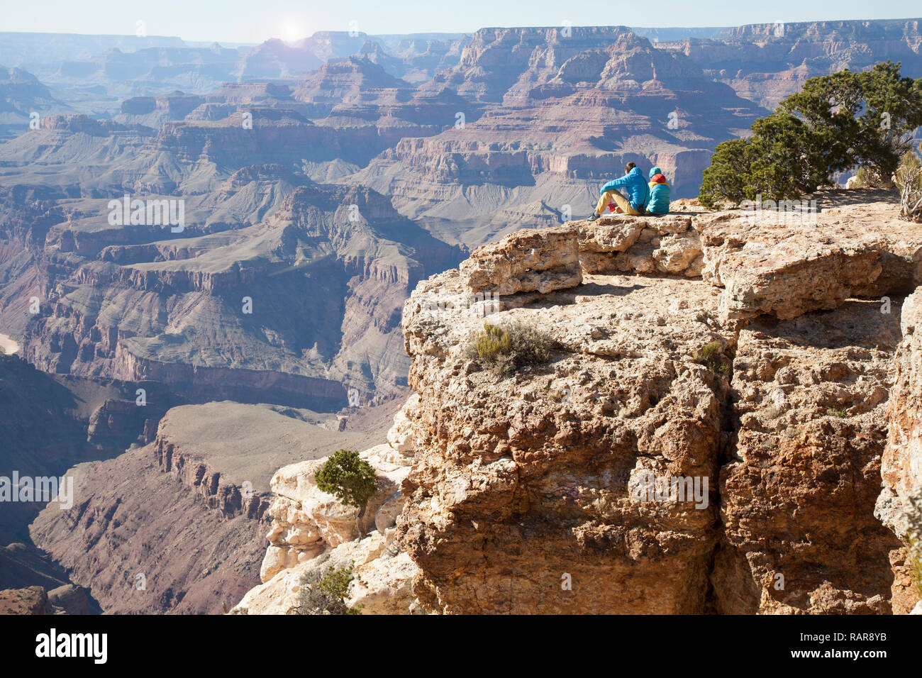 Escursionista giovane seduto a bordo del Grand Canyon godendo le viste Foto Stock