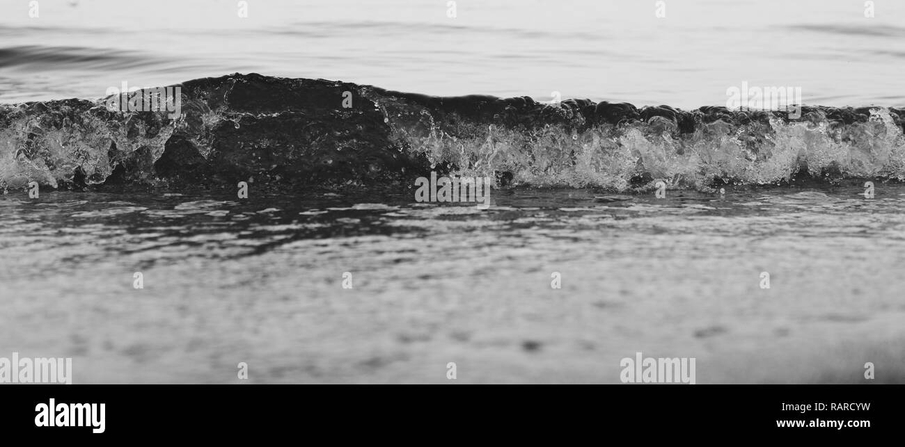 Close up di piccole onde schizzi su di una spiaggia di sabbia Foto Stock