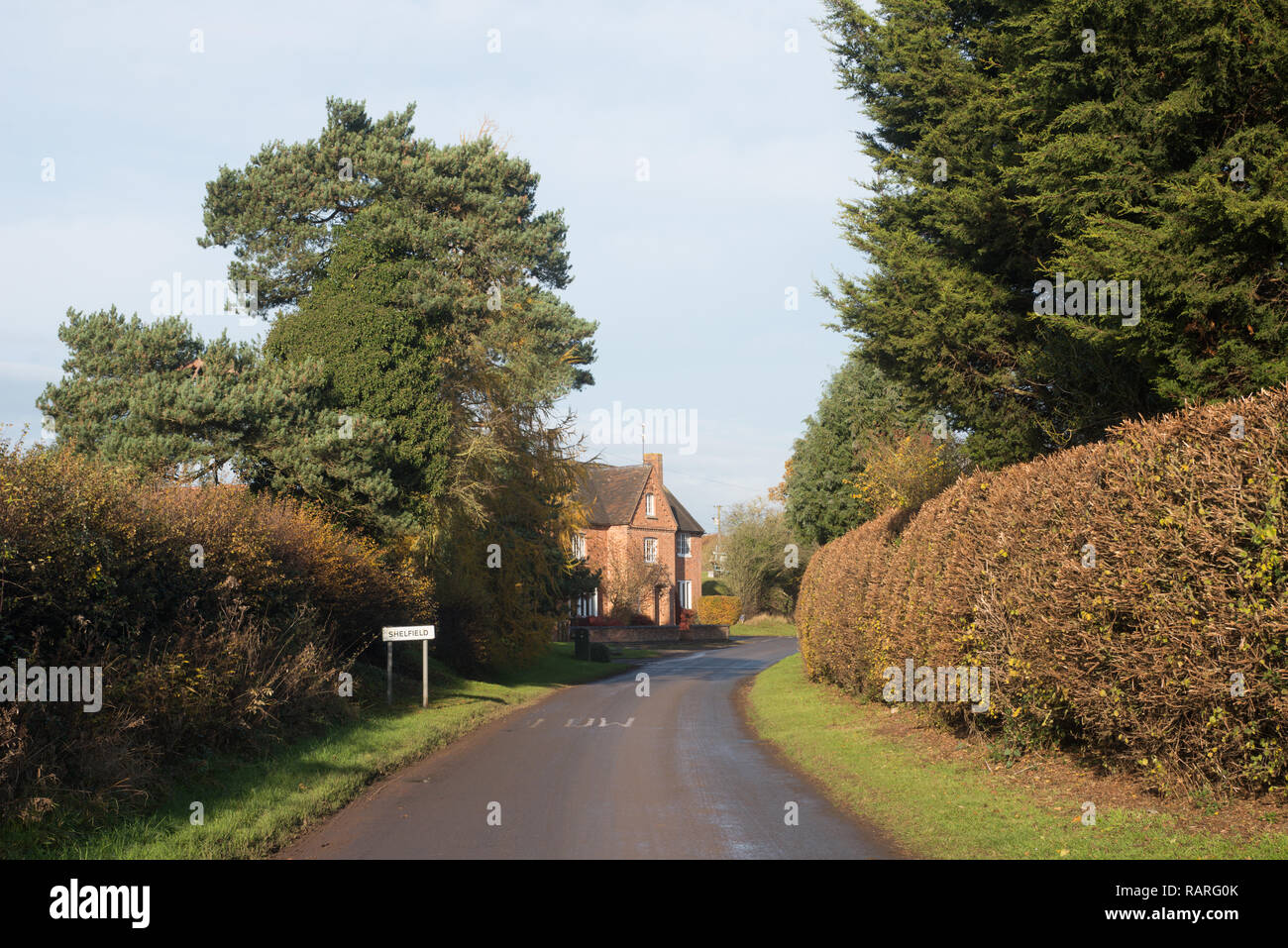 La strada e il segno di villaggio sull'immissione Shelfield, vicino a Alcester, Stratford-su-Avon, Warwickshire, Inghilterra, Regno Unito Foto Stock