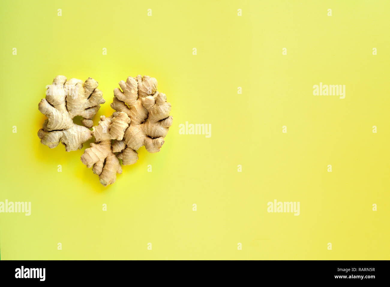 A forma di cuore le radici di zenzero su sfondo giallo Foto Stock