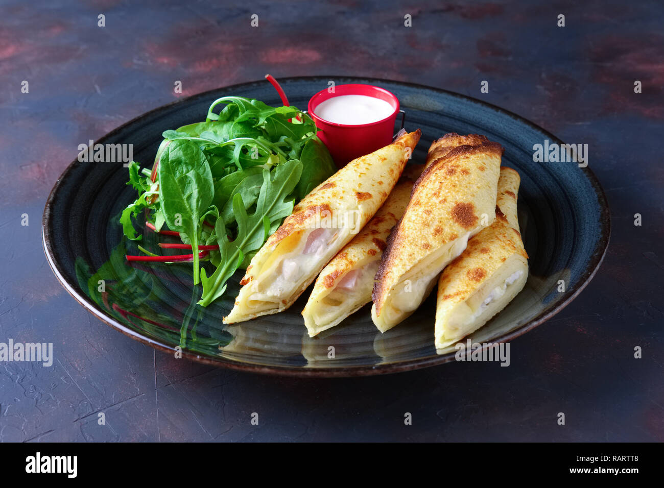 Thin frittelle ripiene con prosciutto e formaggio fuso servita con Spinaci, Rucola, mais e insalata di bietole Foto Stock