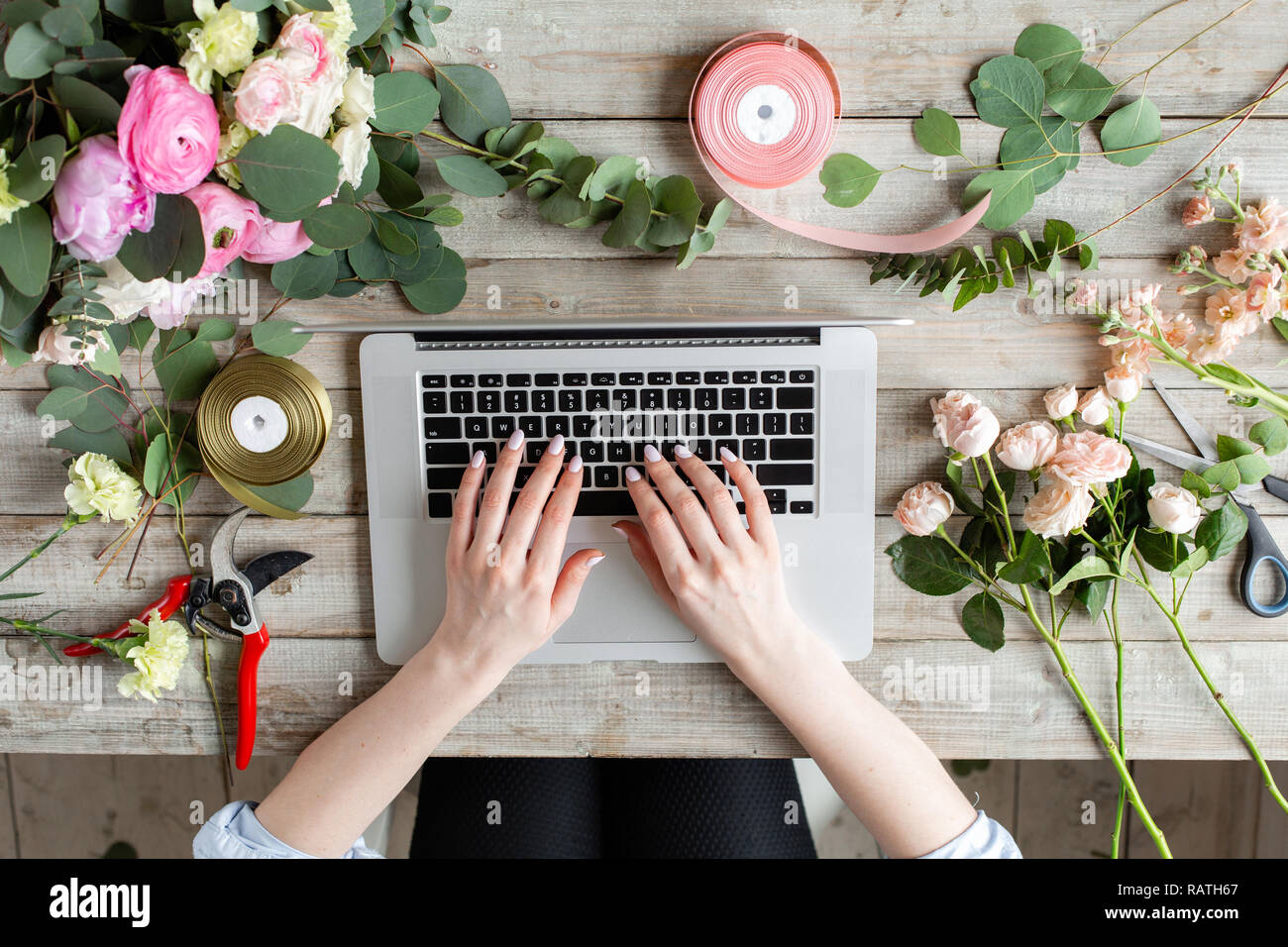Close-up di mani, tastiera portatile e tavola floreale. La donna blogger e creatori di contenuti di social network e blog negozio di fiori. Il concetto di negozio online e di consegna floreale. SMM promozione Foto Stock