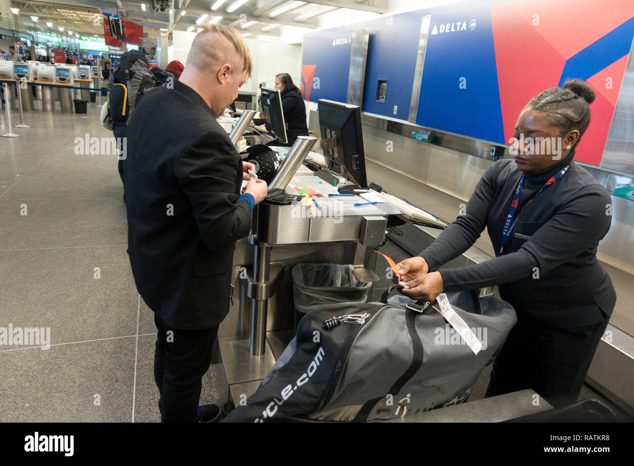 Nero donna agente di viaggio controlli nei viaggiatori internazionali e i suoi bagagli all'Aeroporto Internazionale di Minneapolis St Paul International Airport. Minneapolis Minnesota MN USA Foto Stock