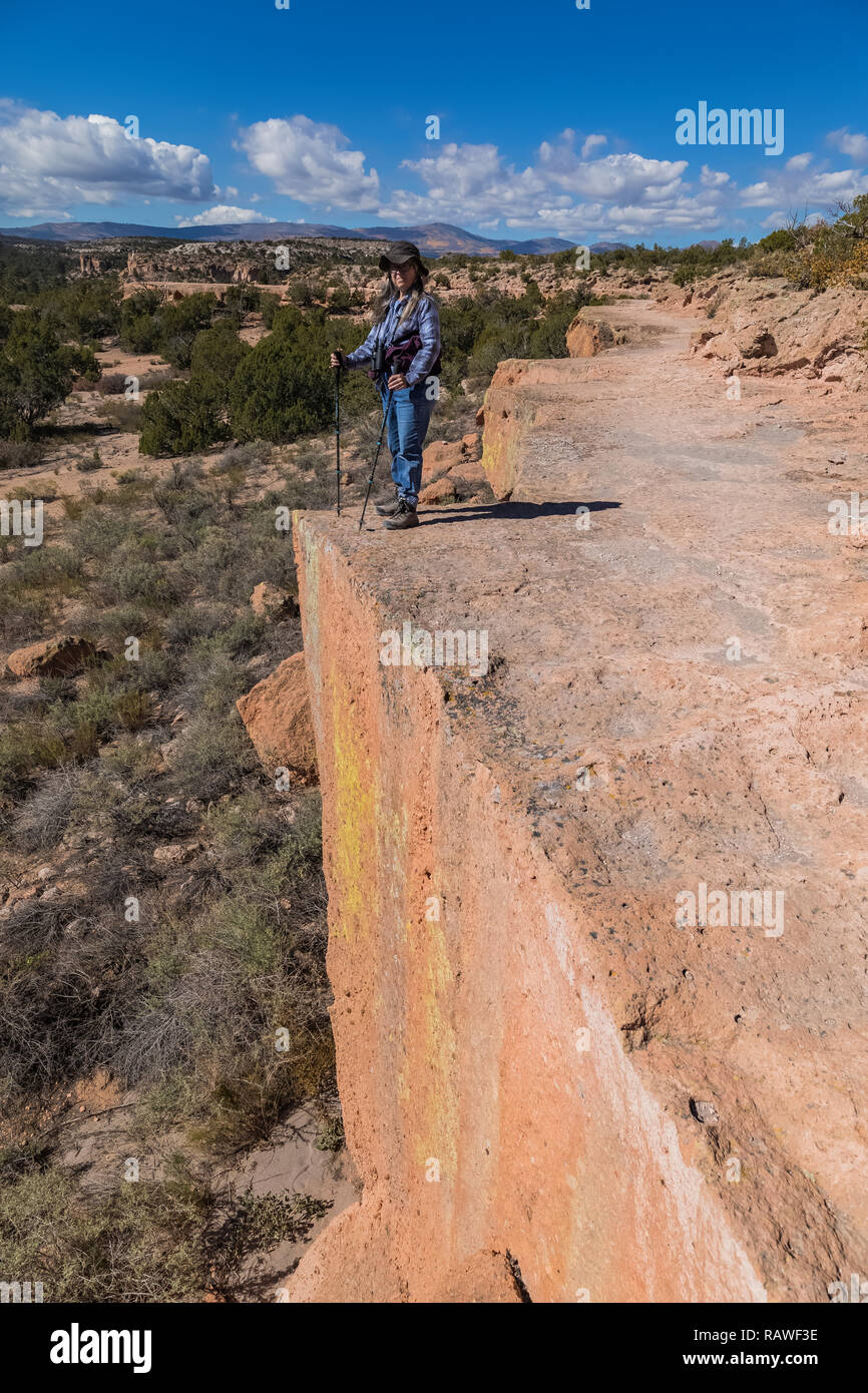 Karen Rentz sul sentiero lungo una scogliera alla Tsankawi siti preistorici Bandelier National Monument vicino a Los Alamos, Nuovo Messico Foto Stock