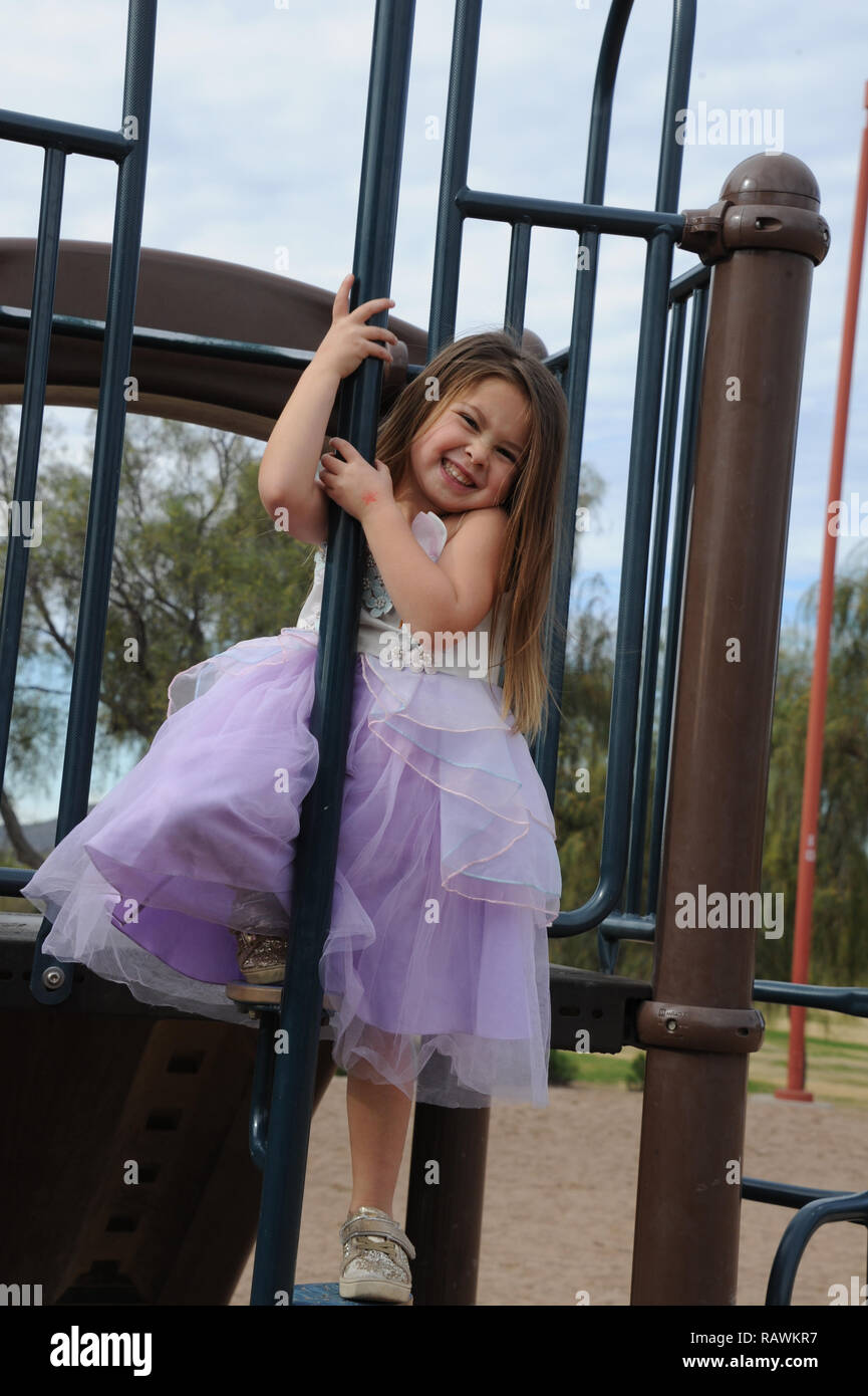 Giovane ragazza presa di un palo su un parco giochi in una principessa abito Foto Stock